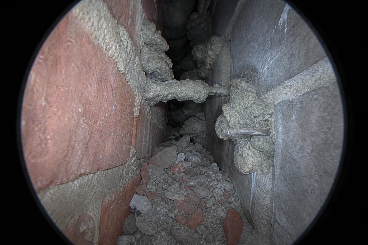 Endoscopisch zicht op mortelbaarden, een mortelbrug en bouwpuin in een vervuilde spouw